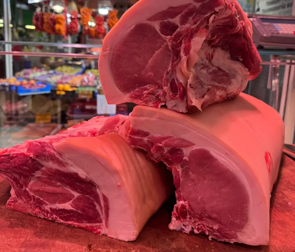 Carré e lonza di maiale sul banco, con il Mercato Trionfale sullo sfondo